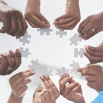 Hands holding puzzle pieces in a circle