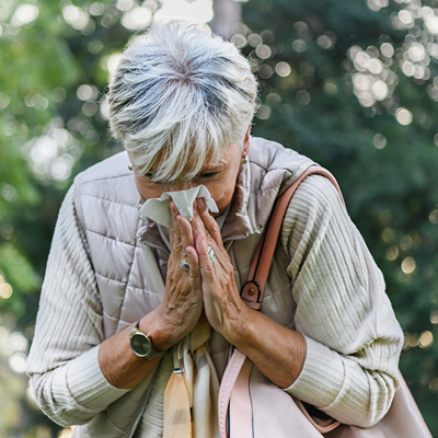 woman blowing her nose outside